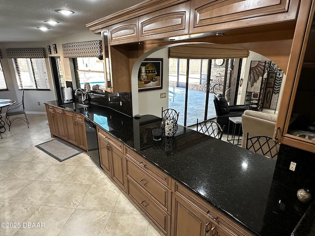 kitchen featuring sink, black dishwasher, dark stone countertops, light tile patterned floors, and a textured ceiling