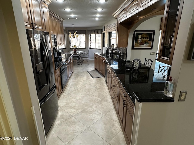 kitchen with sink, a textured ceiling, a notable chandelier, pendant lighting, and black appliances