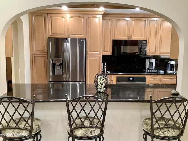 kitchen with tasteful backsplash, kitchen peninsula, dark stone counters, and black appliances