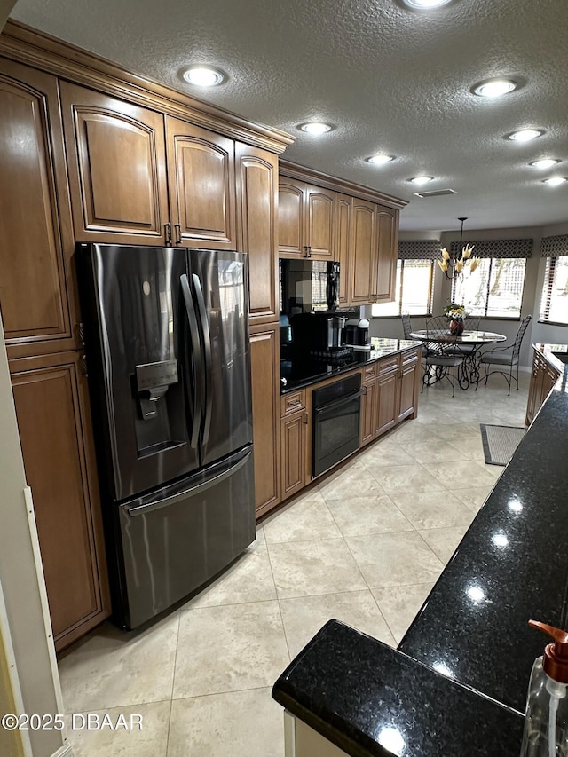 kitchen featuring decorative light fixtures, light tile patterned floors, black appliances, a textured ceiling, and an inviting chandelier