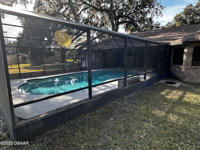 view of pool with a yard and glass enclosure