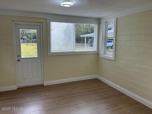 entryway with brick wall and hardwood / wood-style floors