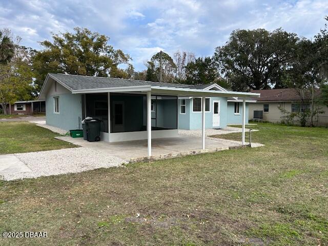 back of house featuring a carport and a lawn