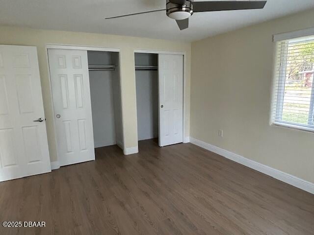 unfurnished bedroom featuring ceiling fan, two closets, and dark hardwood / wood-style floors