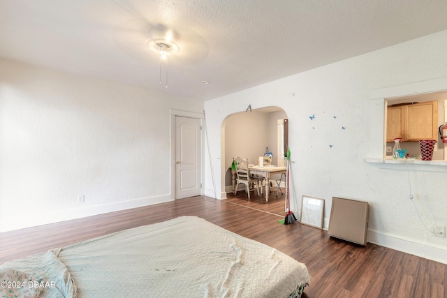 bedroom with a textured ceiling, ceiling fan, and dark wood-type flooring