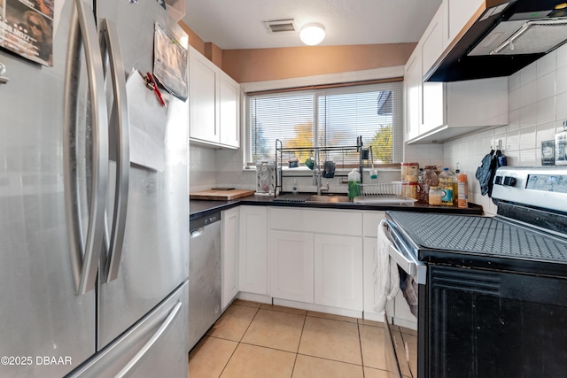 kitchen with white cabinetry, tasteful backsplash, range hood, and appliances with stainless steel finishes