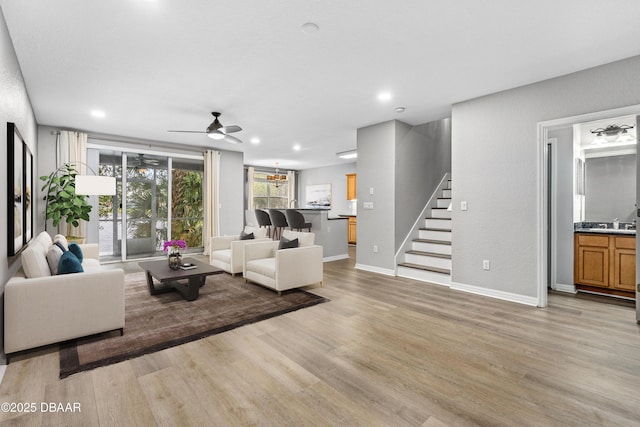 living room featuring ceiling fan, light hardwood / wood-style flooring, and sink