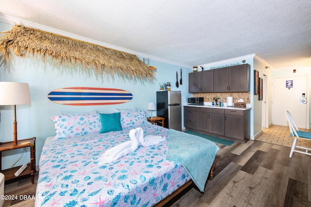 2043 S Atlantic Ave Unit 105, Daytona Beach, FL 32118 - bedroom featuring freestanding refrigerator, a textured ceiling, crown molding, and wood finished floors