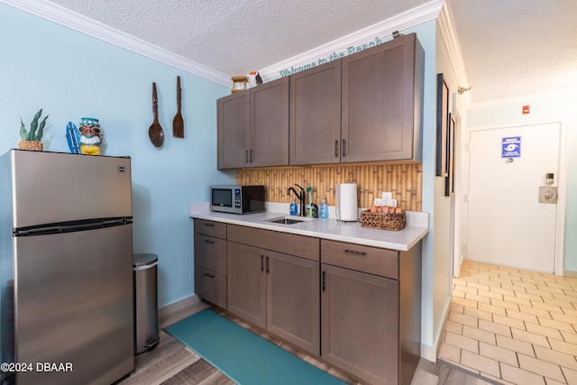 2043 S Atlantic Ave Unit 105, Daytona Beach, FL 32118 - kitchen featuring ornamental molding, light countertops, a textured ceiling, a sink, and appliances with stainless steel finishes
