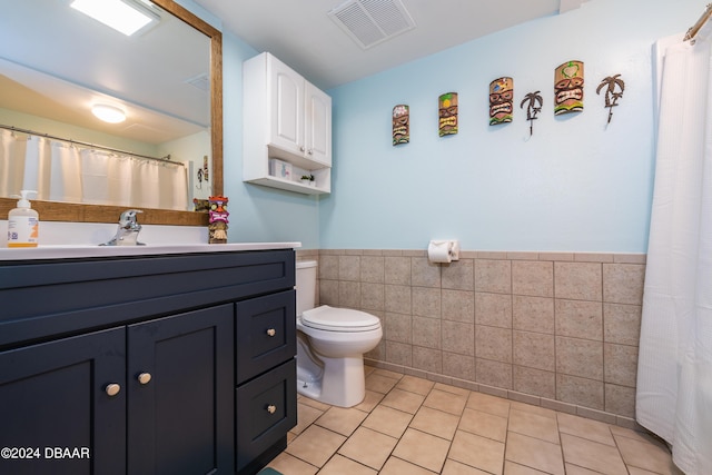 2043 S Atlantic Ave Unit 105, Daytona Beach, FL 32118 - bathroom with visible vents, wainscoting, toilet, tile walls, and tile patterned floors