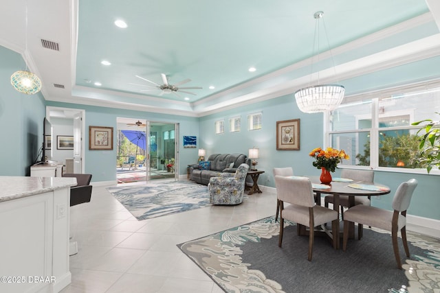 dining room featuring crown molding, a tray ceiling, ceiling fan, and light tile patterned flooring