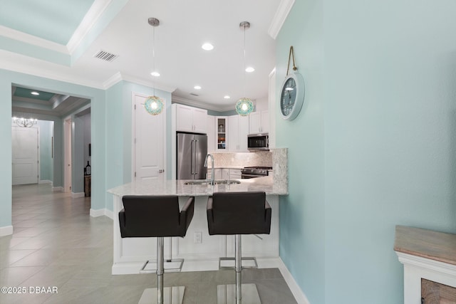 kitchen with premium appliances, ornamental molding, kitchen peninsula, pendant lighting, and white cabinets