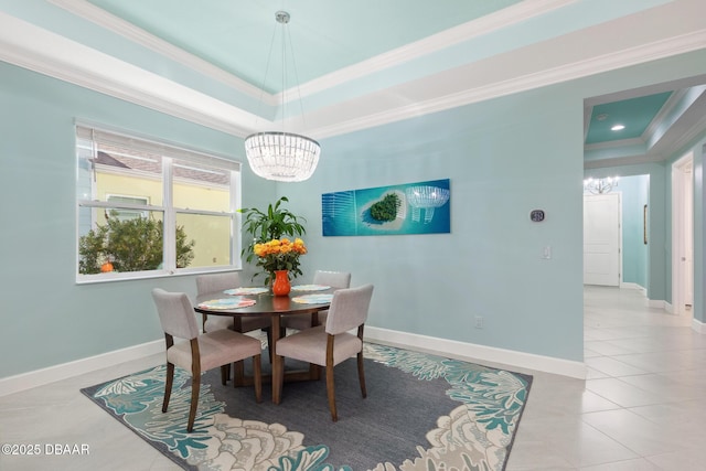 tiled dining space featuring crown molding, a raised ceiling, and an inviting chandelier