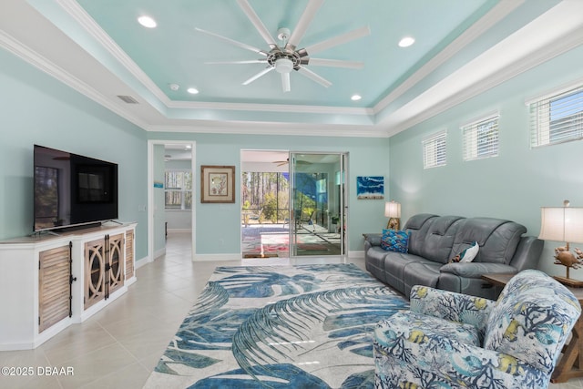 tiled living room featuring a raised ceiling, crown molding, and ceiling fan