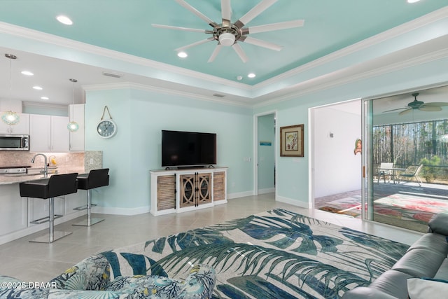 living room with crown molding, a raised ceiling, ceiling fan, and light tile patterned flooring