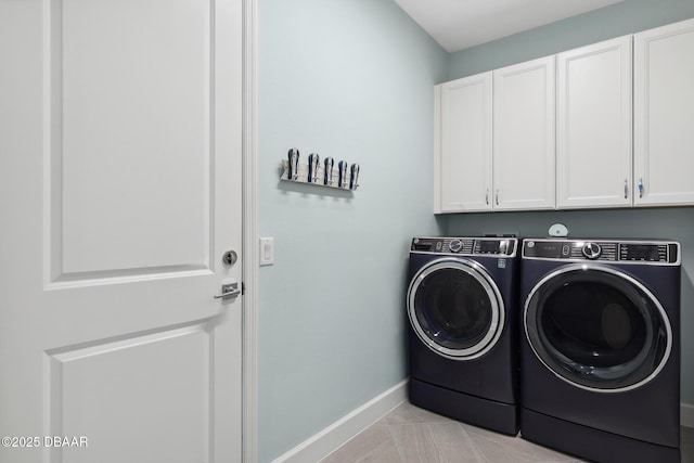 washroom with light tile patterned floors, washer and clothes dryer, and cabinets