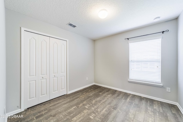 unfurnished bedroom with baseboards, wood finished floors, and a closet
