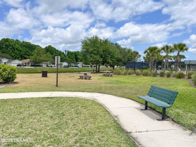 view of property's community with a lawn and fence