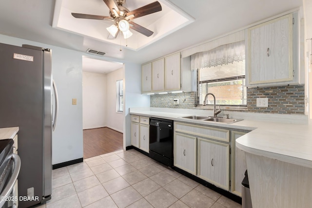 kitchen featuring visible vents, a tray ceiling, a sink, light countertops, and dishwasher