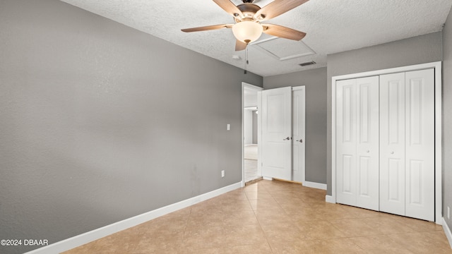 unfurnished bedroom with a textured ceiling, light tile patterned flooring, ceiling fan, and a closet