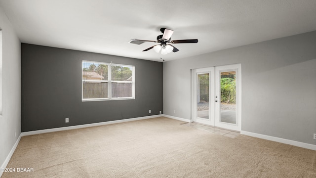 empty room featuring a wealth of natural light, french doors, ceiling fan, and carpet floors