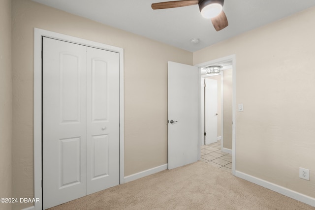 unfurnished bedroom with a closet, light colored carpet, and ceiling fan