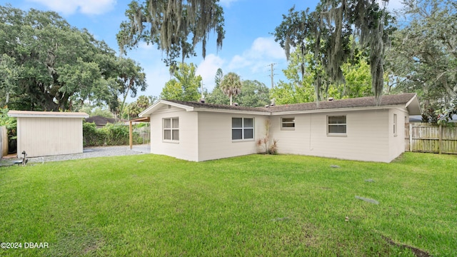 back of house featuring a storage shed and a lawn