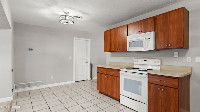 kitchen featuring white appliances, a textured ceiling, and light tile patterned floors