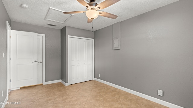 unfurnished bedroom featuring a textured ceiling, light tile patterned floors, ceiling fan, and a closet