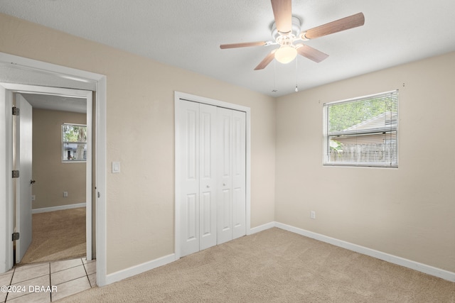 unfurnished bedroom with a closet, multiple windows, light carpet, and ceiling fan