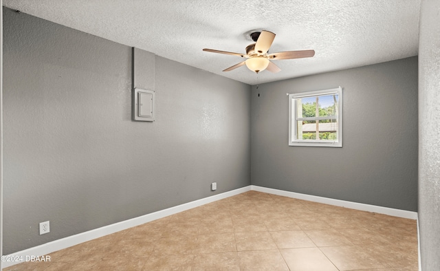 empty room with a textured ceiling, ceiling fan, and light tile patterned floors