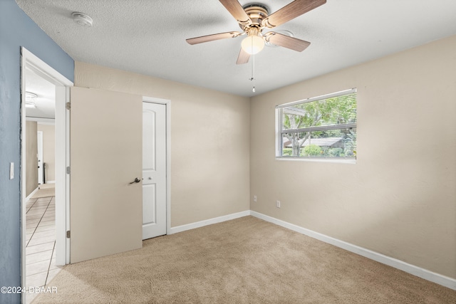 carpeted empty room featuring ceiling fan and a textured ceiling