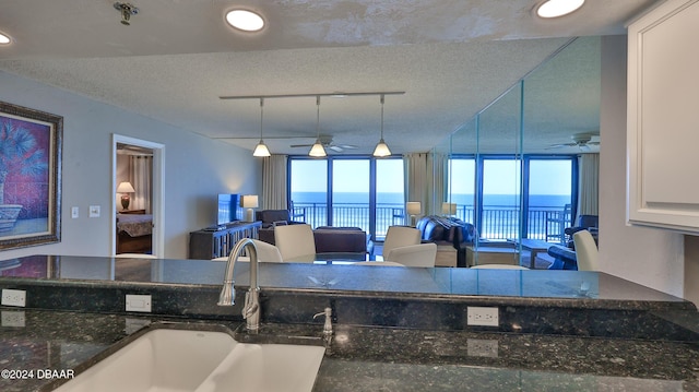4139 S Atlantic Ave Unit A406, New Smyrna Beach, FL 32169 - kitchen featuring a ceiling fan, open floor plan, a textured ceiling, dark stone countertops, and recessed lighting