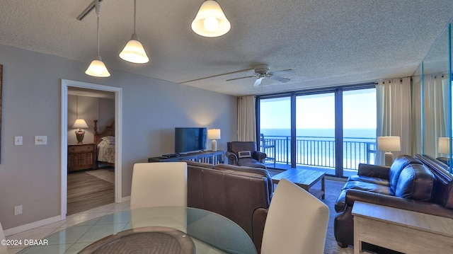 4139 S Atlantic Ave Unit A406, New Smyrna Beach, FL 32169 - living room with a textured ceiling, ceiling fan, light tile patterned floors, and a wall of windows