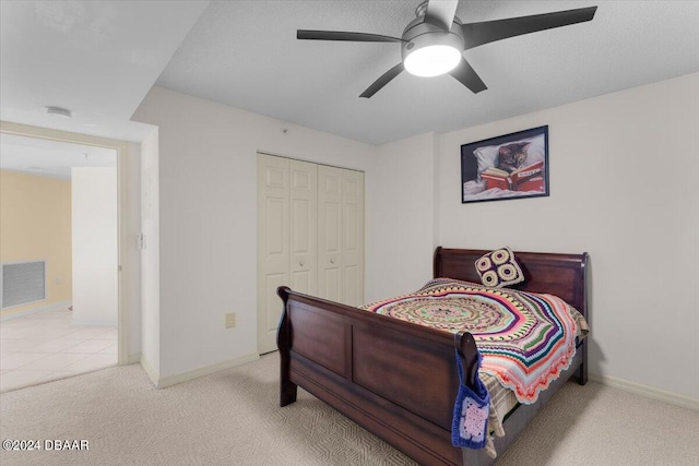 bedroom featuring light colored carpet, ceiling fan, and a closet