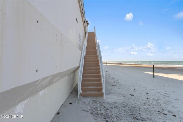 staircase featuring a beach view and a water view