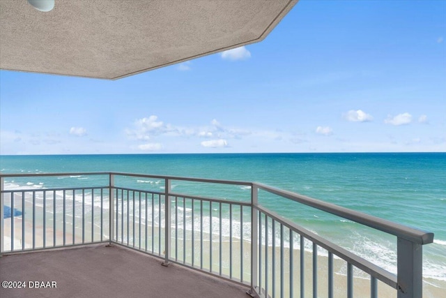 balcony featuring a view of the beach and a water view