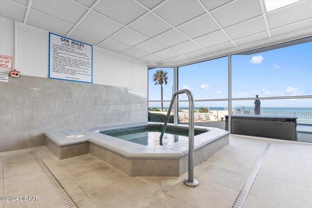 view of swimming pool featuring a water view and an indoor in ground hot tub