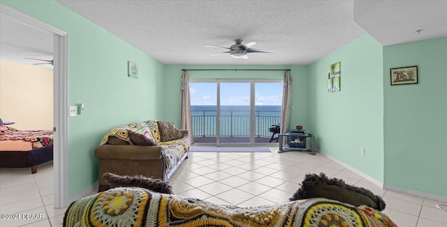 tiled living room featuring ceiling fan, a textured ceiling, and a water view