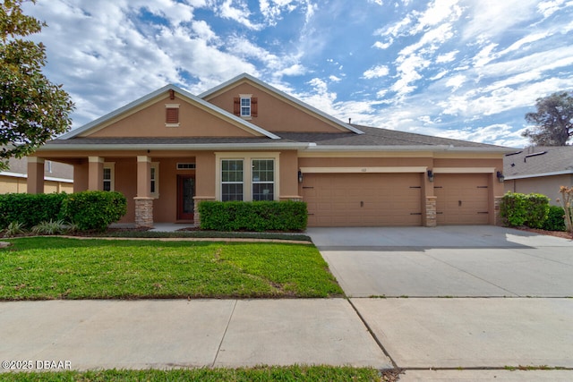 view of front of property with driveway, stone siding, stucco siding, an attached garage, and a front yard