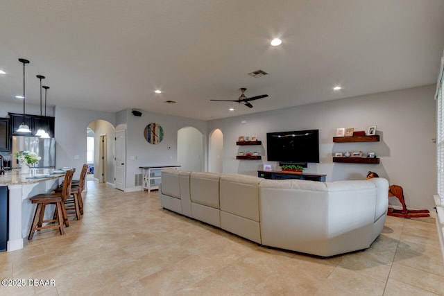 living room with arched walkways, recessed lighting, visible vents, a ceiling fan, and baseboards