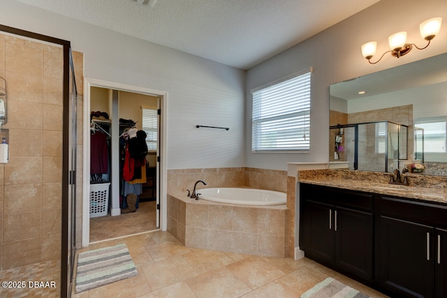 bathroom featuring a garden tub, a spacious closet, a textured ceiling, vanity, and a shower stall