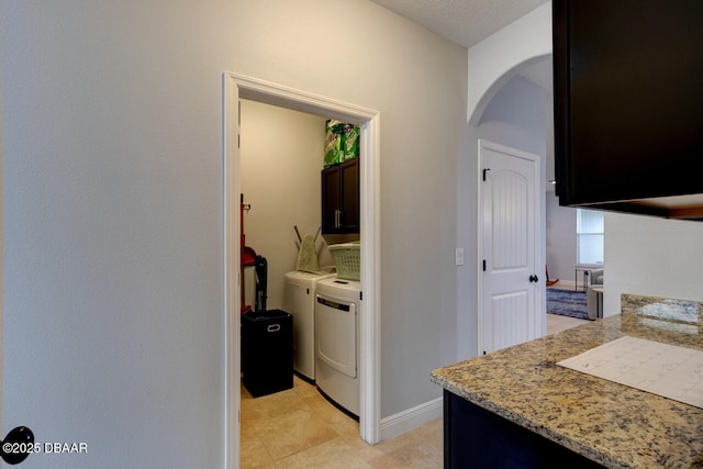 hall featuring baseboards, arched walkways, and separate washer and dryer