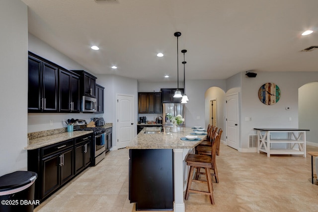 kitchen featuring stainless steel appliances, arched walkways, visible vents, and a sink