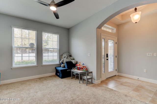 entryway with arched walkways, light carpet, baseboards, and light tile patterned floors