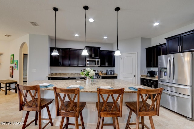 kitchen with visible vents, arched walkways, a kitchen breakfast bar, light stone countertops, and stainless steel appliances