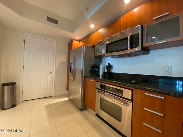 kitchen featuring stainless steel appliances, dark stone countertops, and light tile patterned floors