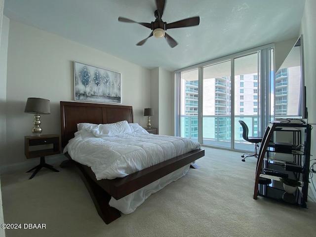 carpeted bedroom with access to exterior, a wall of windows, and ceiling fan