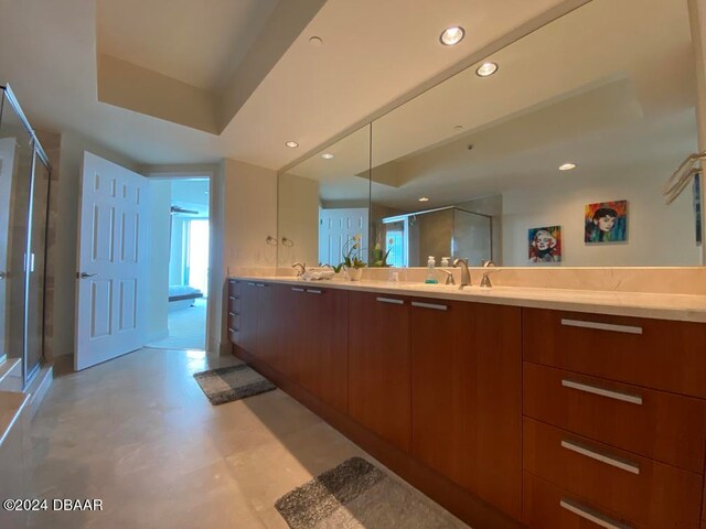 bathroom featuring a shower with shower door and vanity