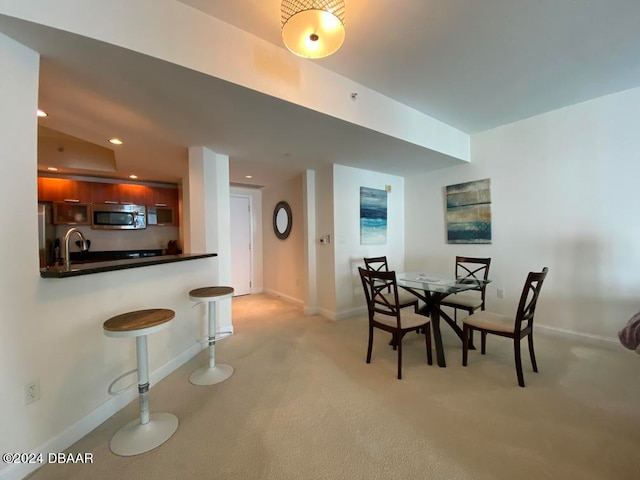 dining space with lofted ceiling, sink, and light colored carpet